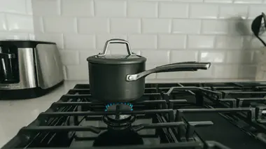 Casserole couverte sur le feu d'une cuisinière à gaz, eau de cuisson que l'on peut récupérer pour le jardin une fois refroidie